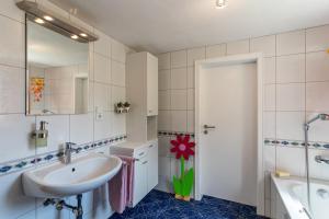 a bathroom with a sink and a mirror and a tub at Haus Am Waldrand in Schenkenzell +25 photos