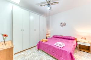 a bedroom with a pink bed and white cabinets at E case e Leviche in Castrignano del Capo