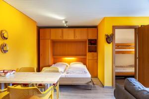 a room with a bed and a table and yellow walls at Haus Excelsior Top 2 in Seefeld in Tirol