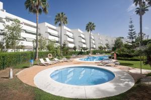 a large swimming pool with lounge chairs and a building at Guadalmina Baja in Marbella