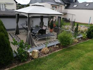 een achtertuin met een prieel met stoelen en een parasol bij Bellevie in Kell