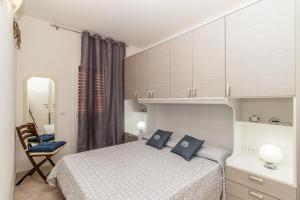 a bedroom with a bed and a chair and a mirror at Frisaia F3 in Isola Rossa