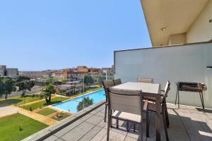 a table and chairs on a balcony with a view of a pool at Sublime Mundo Apartamento in Apúlia