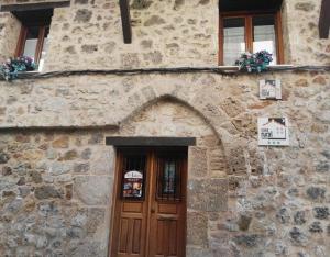 a stone building with a wooden door and windows at Juderia I in Oña