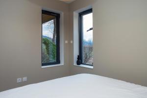 a bedroom with two windows and a bed at Appart bureau in Le Touvet