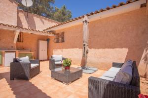 a patio with chairs and an umbrella and a table at Maison - La Lieutenante in Puget-sur-Argens