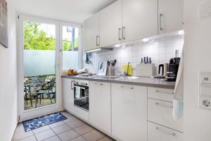 a white kitchen with white cabinets and a window at Ferienhaus Schwalbennest in Lörrach