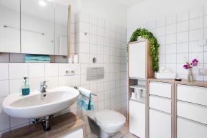 a white bathroom with a sink and a toilet at Ferienhaus Schwalbennest in Lörrach +18 photos
