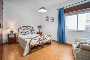 a bedroom with a bed and a chair and a window at Apartamento Escadinhas in Lagos