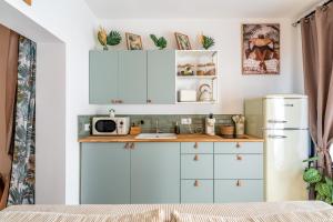 a kitchen with white cabinets and a refrigerator at Une parenthèse en luberon, jacuzzi in Les Taillades