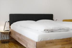 a bed with a black headboard and white sheets at Haus Mader 3 in Riscone +8 photos