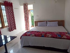 a bedroom with a large bed with red sheets and windows at Alhind Residency , Valara, Munnar in Munnar +10 photos