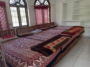 a large bed in a room with two windows at Alhind Residency , Valara, Munnar in Munnar
