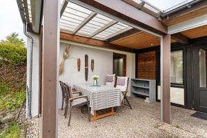 a patio with a table and chairs and a glass roof at Bungalow Nordschwarzwald in Schellbronn