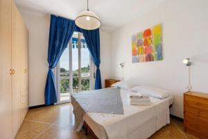 a bedroom with a bed with blue curtains and a window at Ca Giannina in Bonassola