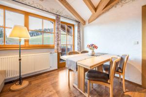 a dining room with a table and chairs and a lamp at Haus zur Vogelweide App 6 in Dobbiaco
