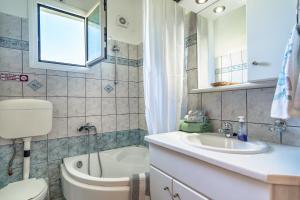 a bathroom with a toilet and a sink and a tub at Makis Apartment Katelios in Khionáta