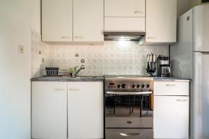 a kitchen with white cabinets and a stove at Makis Apartment Katelios in Khionáta +12 photos