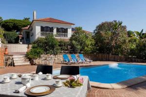 a table with chairs next to a swimming pool at Cottage Sete Mares in Colares