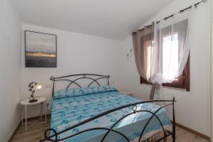 a bedroom with a bed with blue sheets and a window at Villa Aloe 2 in Costa Paradiso