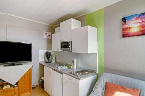 a small kitchen with white cabinets and a tv at Ferienhaus Gerda Wohnung 2 in Westochtersum