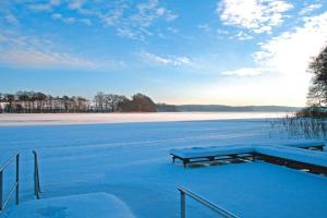 a bench sitting on top of a frozen lake at Blauer Bungalow am See mit Boot in Klein Labenz