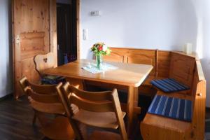 a wooden table with chairs and a vase of flowers on it at Blauer Bungalow am See mit Boot in Klein Labenz