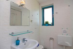 a bathroom with a sink and a mirror and a toilet at Blauer Bungalow am See mit Boot in Klein Labenz +17 photos