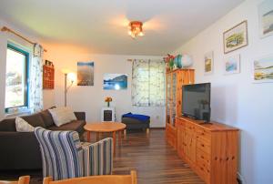 a living room with a couch and a tv at Blauer Bungalow am See mit Boot in Klein Labenz