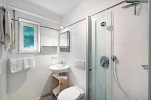 a white bathroom with a sink and a shower at Ferienapartment Remke in Starnberg +17 photos