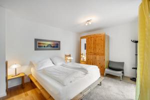 a bedroom with a white bed and a chair at Ferienapartment Remke in Starnberg