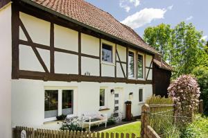 a white cottage with a wooden fence at Ferienwohnung Seelenruhig in Wollershausen
