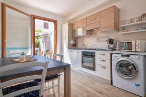 a kitchen with a washing machine and a table with chairs at Holiday Cala Sant'andrea in Stintino