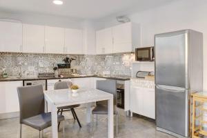a kitchen with white cabinets and a table and a refrigerator at Funchal House in Funchal