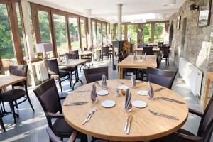 a restaurant with wooden tables and chairs and windows at Hôtel La Ferme de Sy in Ferrières