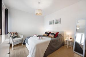 a white bedroom with a bed and a chair at Casa Farol in Portimão