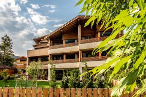 an apartment building with wooden balconies and a fence at Mysciliar Apartment Tree I in Siusi