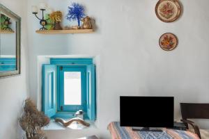 a living room with a blue window and a television at Karai traditional house in Astypalaia