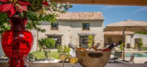 a red vase sitting on a table with wine glasses at Le Mas Du Batadou in Visan +12 photos