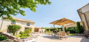 a patio with an umbrella and chairs and a pool at Le Mas Du Batadou in Visan
