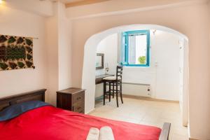 a bedroom with a red bed and a desk at Karai traditional house in Astypalaia