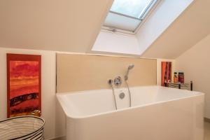 a large white bath tub in a room with a skylight at Dachatelier Überlingen in Überlingen +25 photos