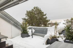 a balcony covered in snow with trees and tables at Dachatelier Überlingen in Überlingen