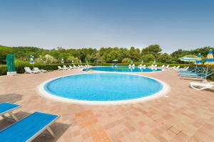 a large swimming pool with chairs and umbrellas at Il Girasole - Limone in Venturina Terme +21 photos