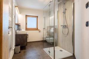 a bathroom with a shower and a toilet and a sink at Planerhof Apartment Enzian in Funes +35 photos