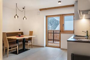 a kitchen and dining room with a table and a window at Planerhof Apartment Enzian in Funes
