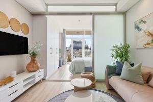 a living room with a couch and a tv at Backup-Powered Trendy City Balcony Apartment in Cape Town +26 photos
