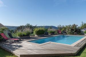 a swimming pool with a deck and chairs next to it at Logement spacieux agréable in Saint-Privat
