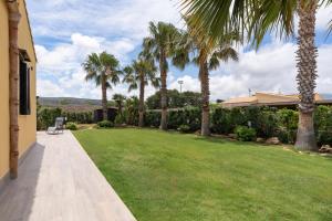 a garden with palm trees and a lawn at Summer Spritz in Custonaci