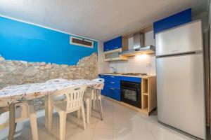 a kitchen with a table and a white refrigerator at Villetta Simius in Villasimius